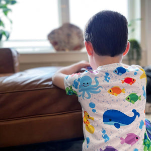 Boy facing away from camera wearing a t-shirt with fish and other sea creatures on it